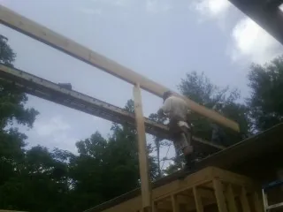 Carpenter setting a ridge beam over a new addition frame — Ice Dam Removal by Roofing Brothers in Eldon